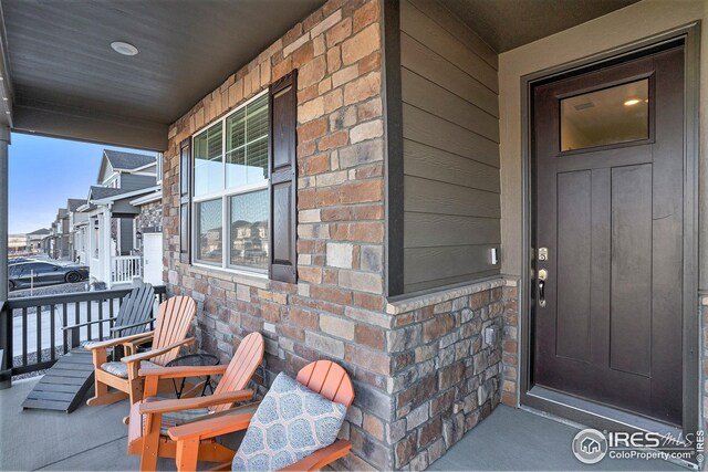 view of exterior entry with stone siding and a porch