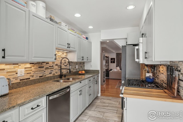 kitchen featuring white cabinetry, sink, dark stone countertops, and dishwasher