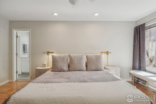 bedroom with hardwood / wood-style flooring, multiple windows, and ensuite bath