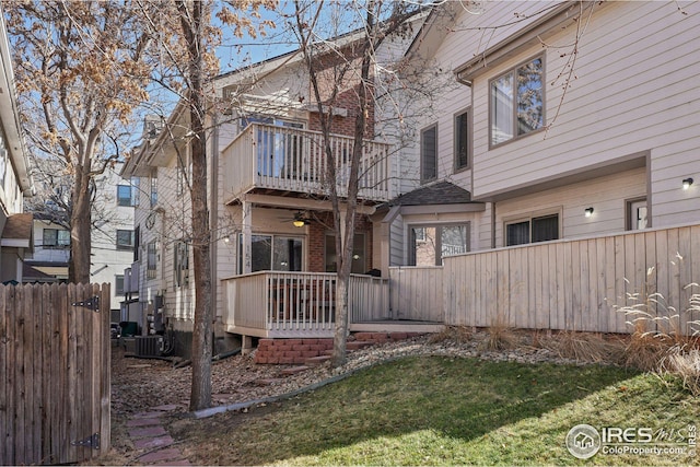 back of property featuring a balcony, ceiling fan, and a lawn