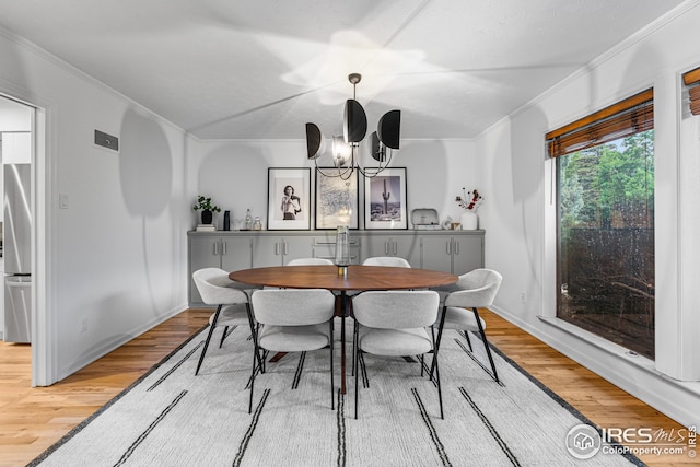 dining room with crown molding, wood-type flooring, and a chandelier