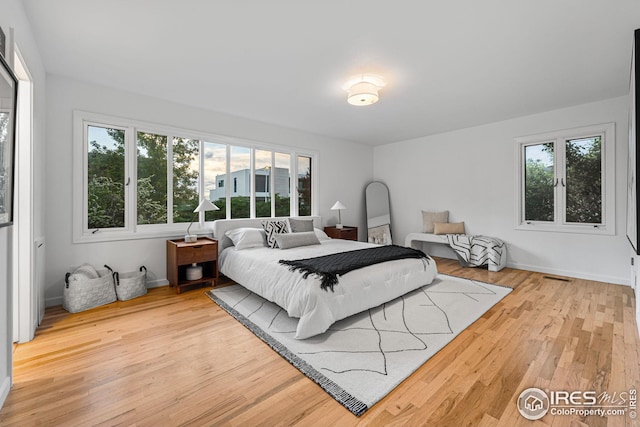 bedroom with multiple windows and light hardwood / wood-style flooring