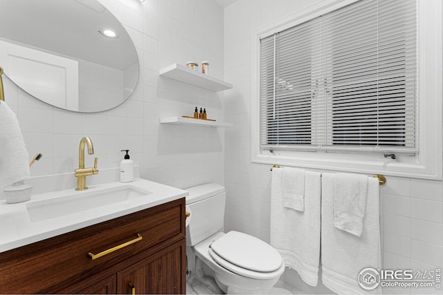 bathroom featuring vanity, tile walls, and toilet