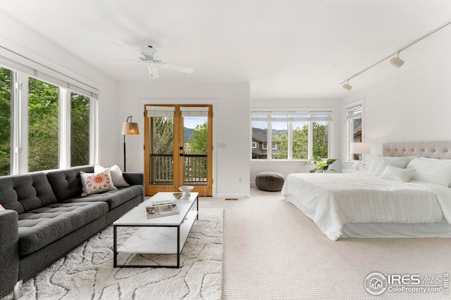 carpeted bedroom featuring ceiling fan, track lighting, and access to outside