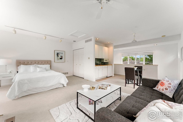 carpeted bedroom with track lighting, ceiling fan, and a closet