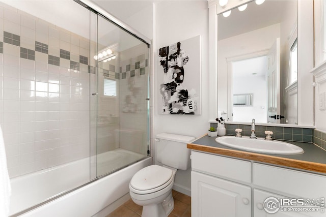 full bathroom featuring vanity, tile patterned floors, shower / bath combination with glass door, and toilet