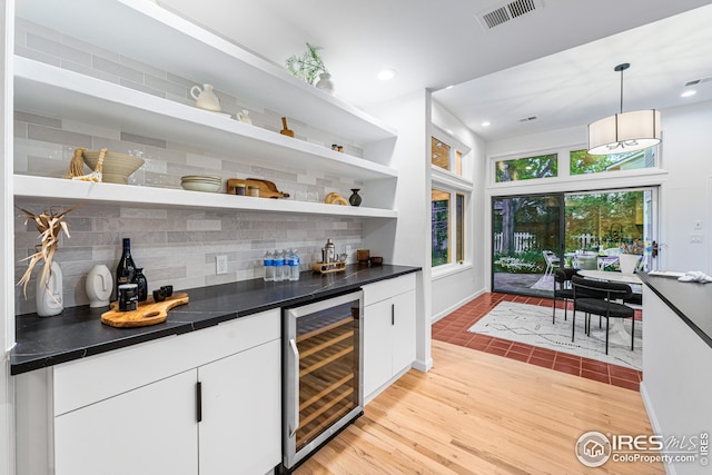 bar featuring light hardwood / wood-style flooring, wine cooler, tasteful backsplash, white cabinets, and decorative light fixtures