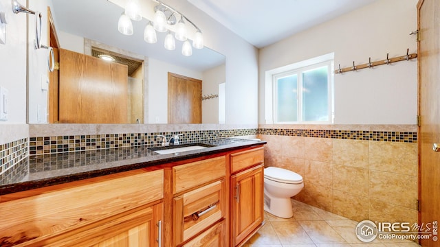 bathroom featuring tile patterned flooring, vanity, toilet, and tile walls