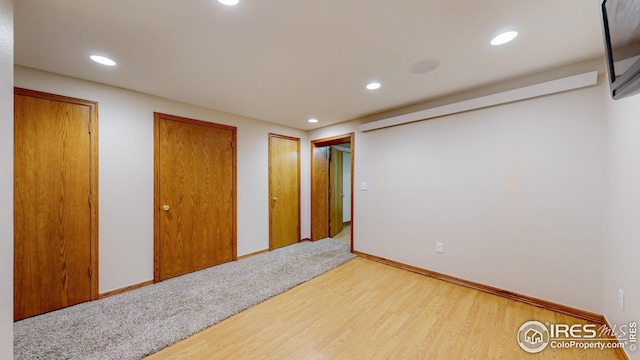 unfurnished bedroom with wood-type flooring and two closets