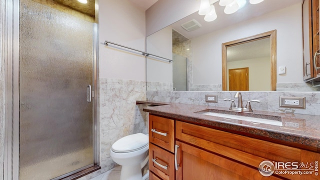 bathroom with vanity, toilet, tile walls, and walk in shower