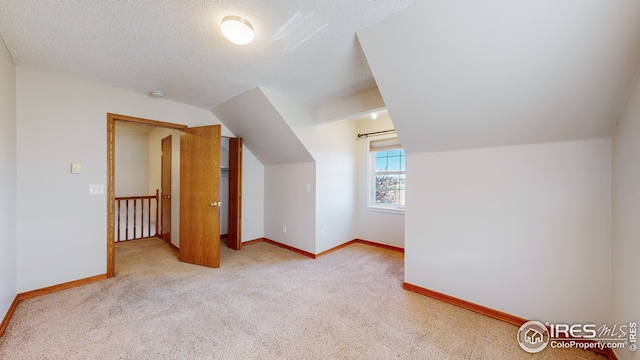 additional living space featuring light carpet, vaulted ceiling, and a textured ceiling