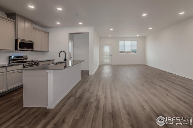 kitchen featuring appliances with stainless steel finishes, gray cabinets, a kitchen island with sink, and sink