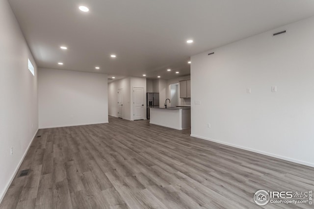 unfurnished living room with sink and light hardwood / wood-style flooring