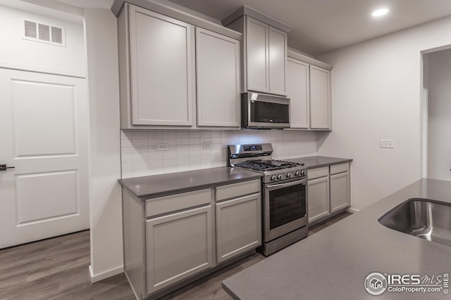 kitchen featuring gray cabinetry, backsplash, sink, and appliances with stainless steel finishes