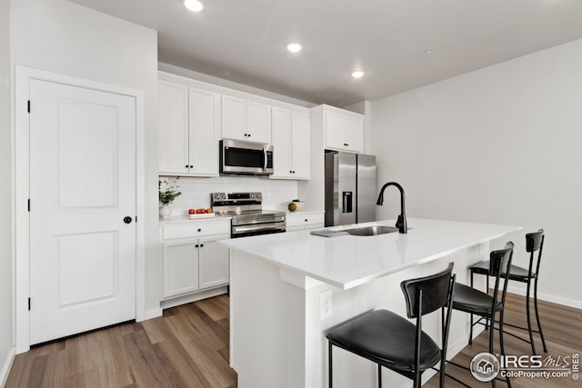 kitchen featuring a kitchen bar, stainless steel appliances, and a center island with sink