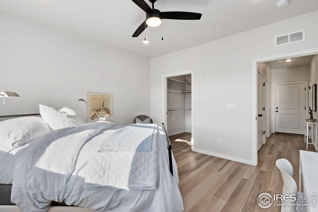 bedroom featuring a spacious closet, light hardwood / wood-style flooring, a closet, and ceiling fan