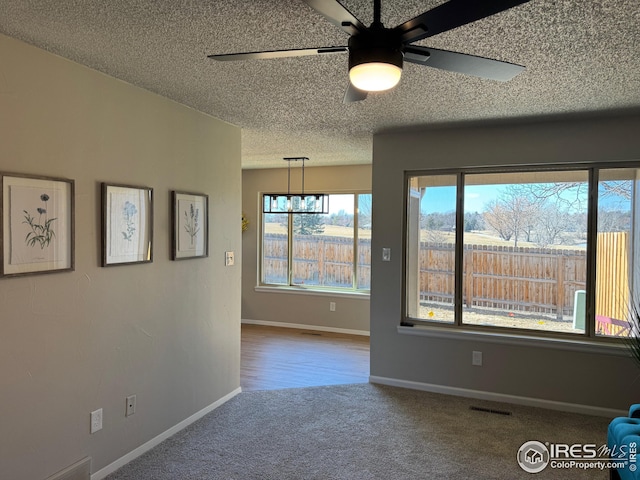 empty room featuring ceiling fan, carpet, and a textured ceiling