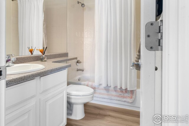 full bathroom with vanity, hardwood / wood-style floors, toilet, and shower / bath combo with shower curtain