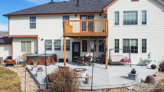 back of property featuring a balcony, a patio, a hot tub, and a fire pit