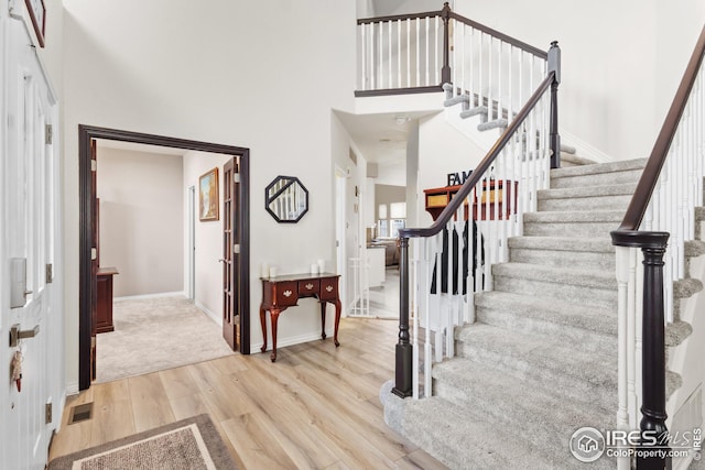 foyer featuring a towering ceiling and light hardwood / wood-style floors