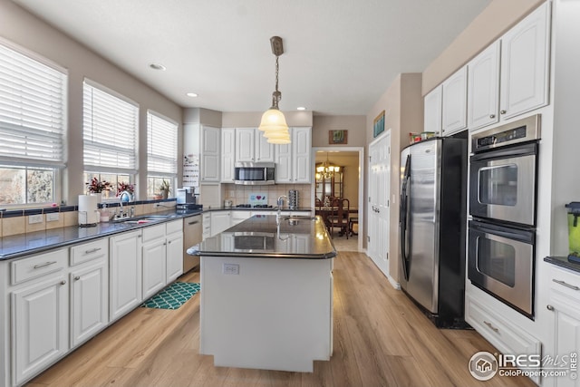 kitchen featuring an island with sink, sink, white cabinets, backsplash, and stainless steel appliances