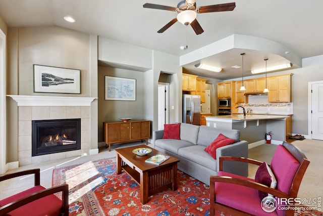 living room with a raised ceiling, baseboards, light colored carpet, ceiling fan, and a tile fireplace