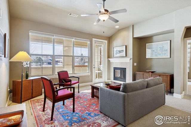 carpeted living area with baseboards, a fireplace, visible vents, and ceiling fan