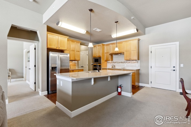 kitchen with a sink, stainless steel appliances, light brown cabinetry, and light countertops