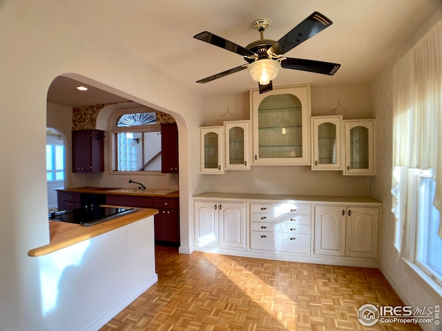 kitchen featuring sink, decorative backsplash, black electric stovetop, ceiling fan, and light parquet flooring