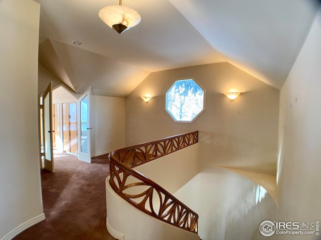 hallway with dark carpet and vaulted ceiling