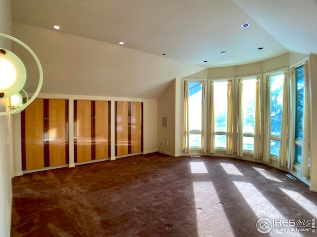 bonus room featuring lofted ceiling and dark carpet