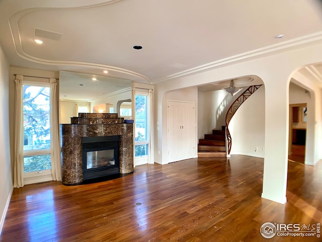 unfurnished living room with a tile fireplace, wood-type flooring, plenty of natural light, and crown molding