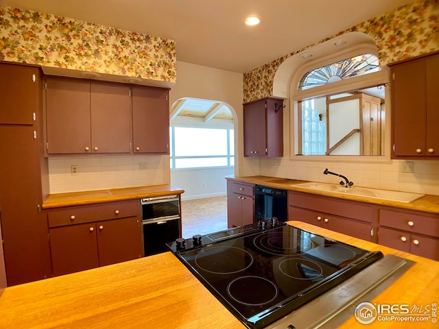 kitchen featuring backsplash, black appliances, and sink