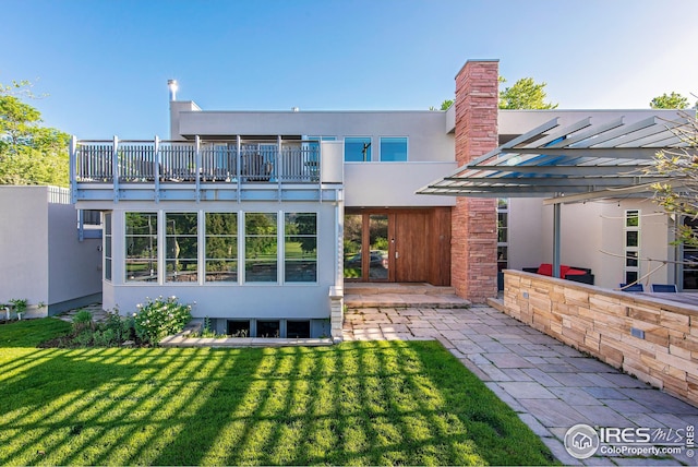 back of house with a balcony, a yard, and a pergola