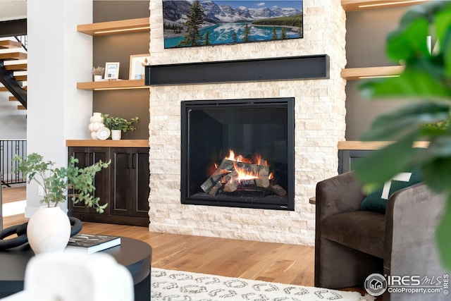living room featuring a fireplace, stairway, and wood finished floors