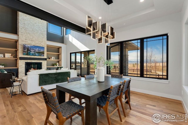 dining space with baseboards, recessed lighting, a stone fireplace, and light wood-style flooring