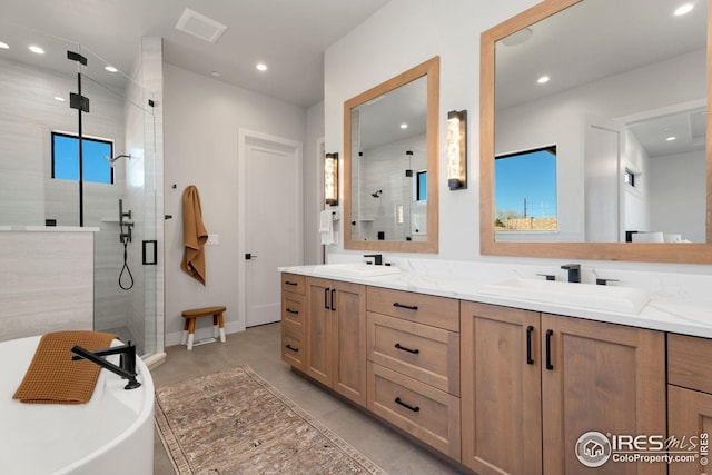 bathroom with a stall shower, double vanity, and a sink