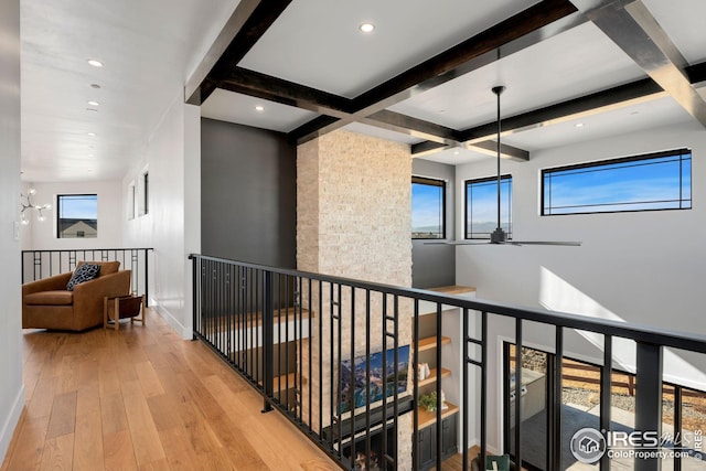 hall featuring beam ceiling, baseboards, an upstairs landing, and wood-type flooring