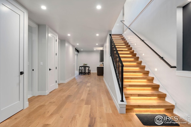 staircase with wood finished floors, recessed lighting, and baseboards