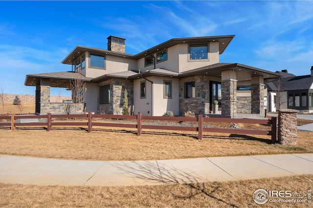 exterior space featuring fence private yard, stone siding, stucco siding, and a chimney