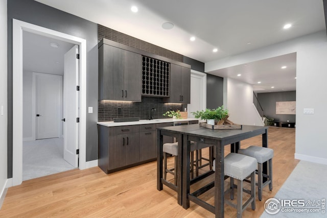 kitchen featuring light wood finished floors, recessed lighting, decorative backsplash, light countertops, and baseboards