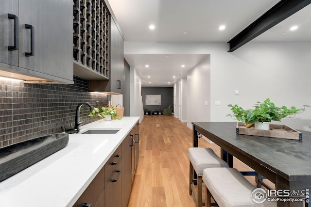 kitchen featuring decorative backsplash, light countertops, light wood finished floors, a sink, and modern cabinets