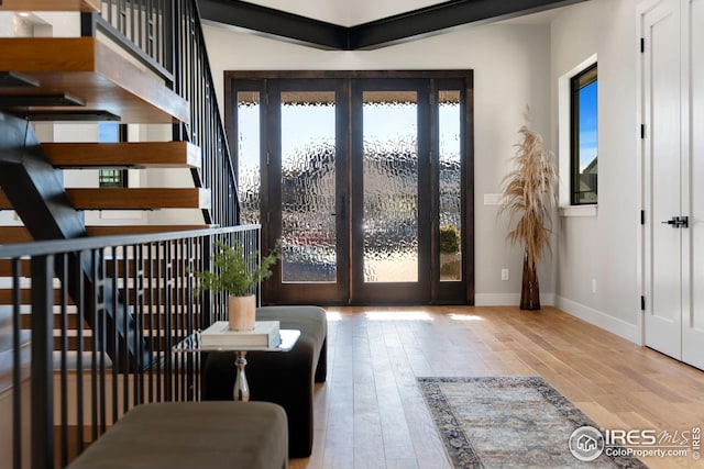 entryway with wood finished floors, french doors, stairs, and baseboards
