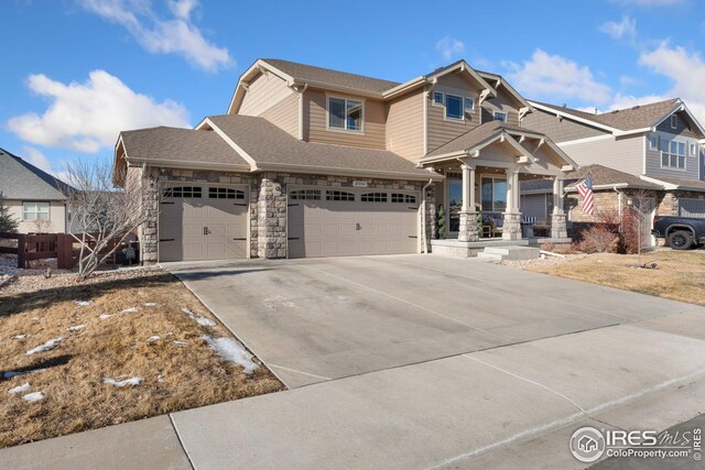 craftsman-style home featuring driveway, stone siding, a shingled roof, and a garage