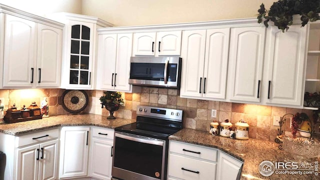 kitchen with white cabinetry, tasteful backsplash, stainless steel appliances, and dark stone counters