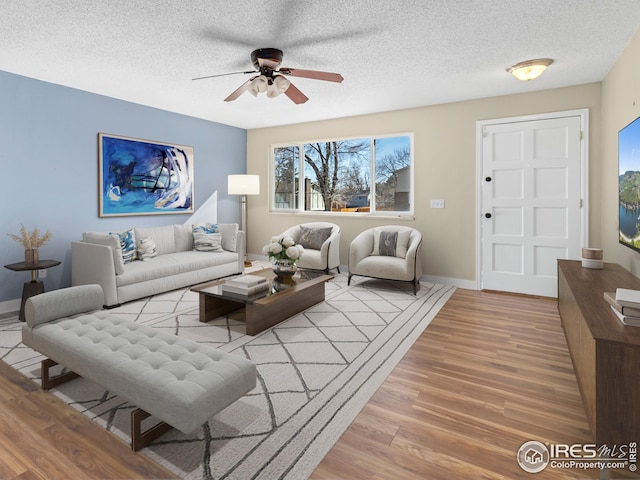 living room featuring ceiling fan, wood-type flooring, and a textured ceiling