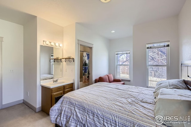 bedroom with light carpet, sink, and ensuite bathroom