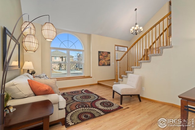 living room featuring an inviting chandelier, lofted ceiling, and light hardwood / wood-style flooring