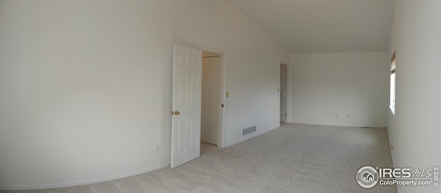 spare room featuring lofted ceiling and light colored carpet