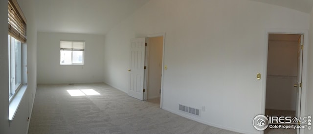 carpeted empty room with lofted ceiling